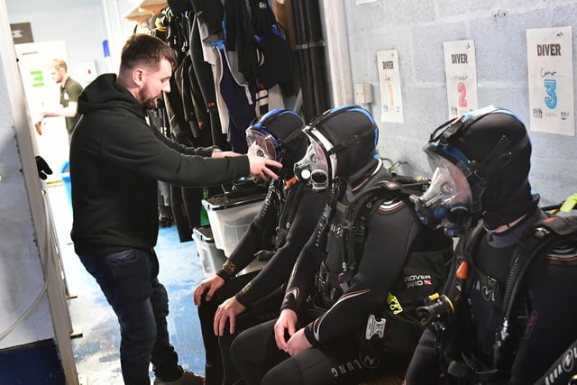 Divers remain seated while instructor Adon Harrison fits the equipment.