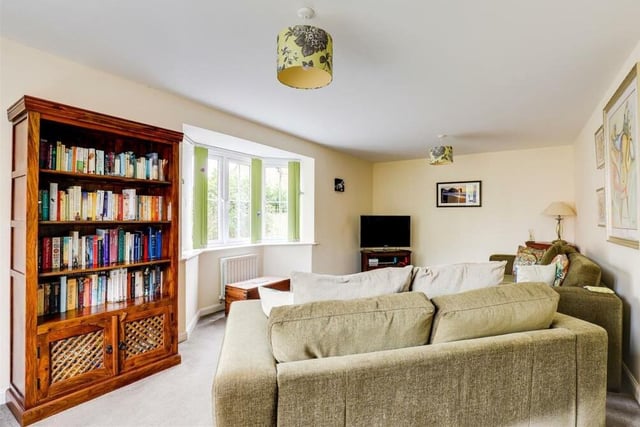 The living room from a different angle, which shows an attractive uPVC double-glazed bay window that overlooks the side of the house. The floor is carpeted, and a TV point is joined by two radiators.