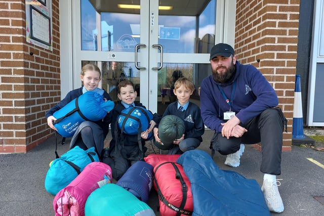 Students and a member of staff at Holy Cross Primary in Hucknall hand over blankets and sleeping bags