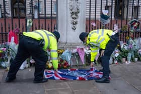 Police officers adjust a Union flag next to tributes to Queen Elizabeth II outside Buckingham Palace (Photo by Carl Court/Getty Images)