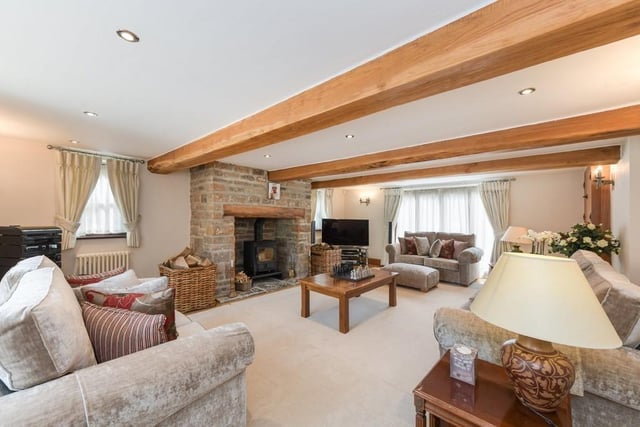 Let's begin our tour of the Linby house in this impressive living room, which is 22 feet in length. It benefits from oak flooring, a large fireplace with a log burner and a window to the front of the property.