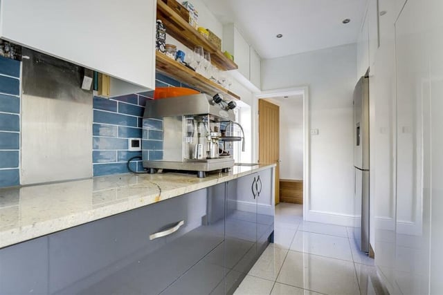 Just off the kitchen is this separate utility room, which boasts a range of fitted gloss base and wall units, an inverted sink, recessed spotlights, tiled splashback and tiled flooring. As you can see, there is space for an American-style fridge/freezer.