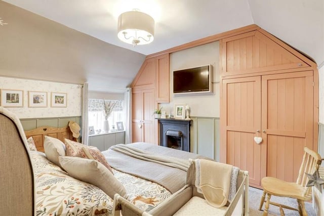 Moving up to the first floor, here is the largest of the two bedrooms, complete with its original open fireplace. Facing the front of the Main Street property, it boasts two built-in wardrobes, feature panelled walls, an in-built cupboard and a carpeted floor.,