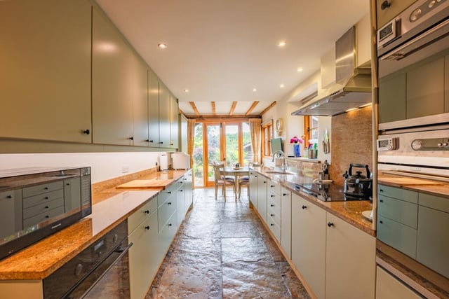 Moving on now to the lengthy, narrow and sleek breakfast kitchen. At one end is space for a small dining or breakfast table, in front of another set of double French doors that flow naturally into the garden