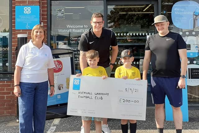 Co-op member pioneer Karen Tennant presents the cheque to Daniel Pheasant and Marcin Sudol with players Harry Pheasant and Oskar Sudol