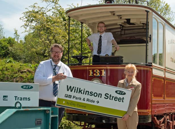 Operations manager Trevor Stocker hands one of the signs to Amanda Blair, marketing and business development manager at Crich Tramway Village with Ryan Breen at the controls of a vintage tram