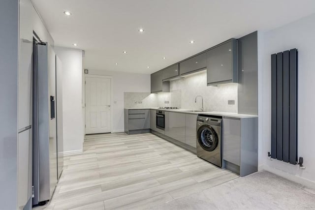 The contemporary kitchen area has a range of fitted base and wall units with worktops, and a stainless steel sink with a swan-neck mixer tap. There is space and plumbing too for a washing machine.