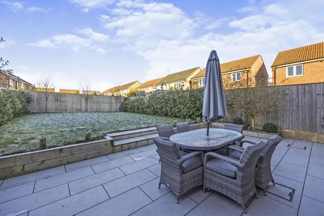 The last photo in our gallery offers a quick peek at the back garden, which is enclosed by timber fencing. A porcelain patio is an ideal seating area for summer entertaining or relaxing, and steps lead to a lawn bordered by mature trees and shrubs.