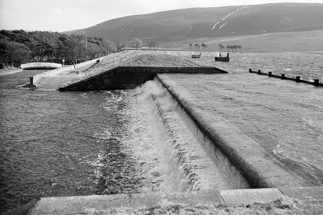 Water pours over the spillway at Thriepmuir Reservoir above Balerno in February 1960.