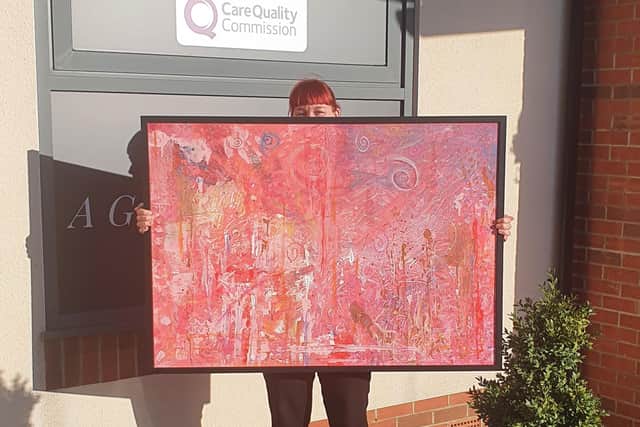 April Towriess, activities coordinator at Fairway View, with the finished Perfectly Pink painting