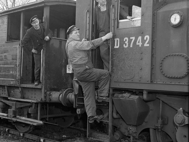 A fireman climbs aboard a train in Balerno in June 1955.
