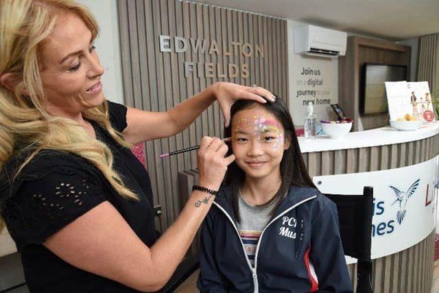 •	Visitor Viney Wong, 11, gets her face painted by Rebecca Knight inside the joint Bovis Homes and L