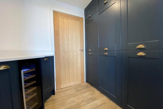 Next to the kitchen is this handy utility room, which even includes a wine fridge. With the decor matching the kitchen, it also features a range of units and a washer/dryer.