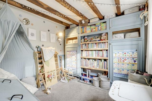 The second reception room at the Papplewick property is currently being used as a children's playroom. It has carpeted flooring, exposed beams to the ceiling and panelled walls.