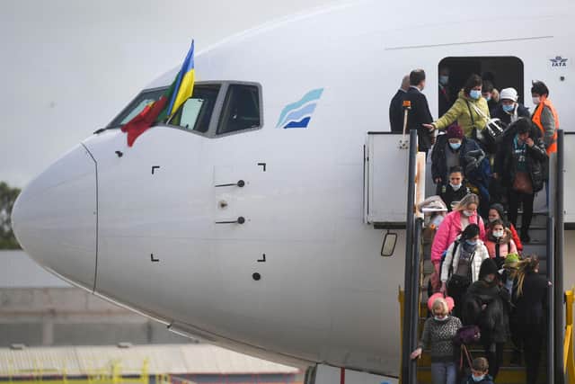 Ukrainian refugees disembark from an aircraft after fleeing their homeland.
