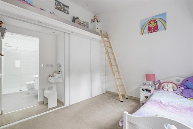 The second bedroom, which also has an en suite, faces the front of the bungalow. It boasts a fitted wardrobe, carpeted flooring, a vertical radiator and recessed spotlights. There is also access to a mezzanine level with a glass balustrade.