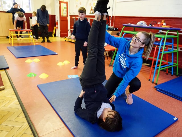 Beth Tweddle Gymnastics at King Edward Primary School. Samantha Scotland schools co-ordinator helps one of the pupils learn a new move.