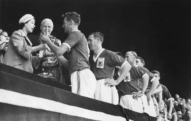 Queen Elizabeth II presents the FA Cup trophy to the captain of Nottingham Forest, Jack Burkitt, after their 2-1 victory over Luton Town in the FA Cup final at Wembley.