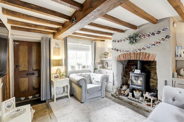 A focal point of the living room is the traditional fireplace, comprising a recessed chimney breast alcove with exposed brick and space for a log-burning stove. The room also includes feature panelled walls, fitted base cupboards in the alcoves and windows to the front and back of the cottage.