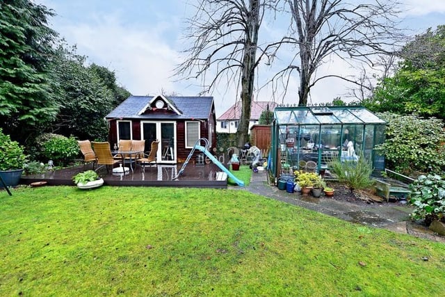 Another delightful area of the garden at the £750,000 property, with a raised, decked patio area in front of a larger summer house.