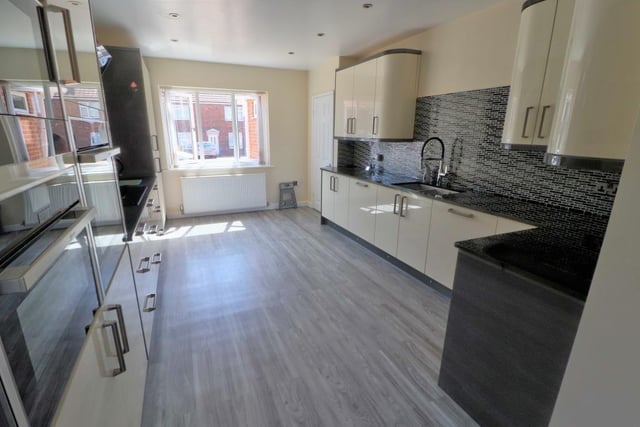 The kitchen also features a host of built-in appliances, including a larder fridge, induction hob, double oven with grills, and integrated microwave. The floor is tiled.