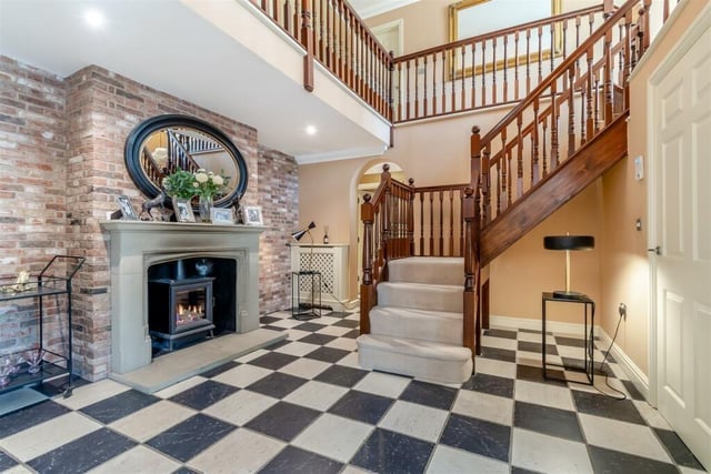 As you step into the £1.2 million Ravenshead property, you are greeted by this magnificent reception hall, with its full-height vaulted ceiling exposure to the first-floor's galleried landing. There is a stone fireplace, with inset gas fire, set against an exposed brick wall, a tiled floor and stylish staircase.