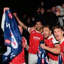 Players and fans of Cheltenham Town celebrate their side's victory outside the ground after gaining promotion to the Sky Bet League One.