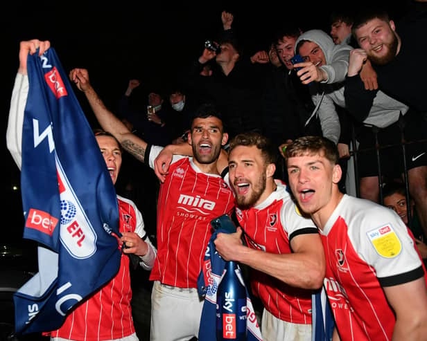 Players and fans of Cheltenham Town celebrate their side's victory outside the ground after gaining promotion to the Sky Bet League One.