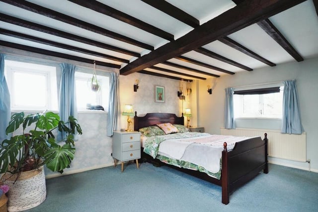 Up to the first floor, where we are greeted by this lovely and spacious master bedroom, complete with ceiling beams, triple-aspect windows and carpeted floor.