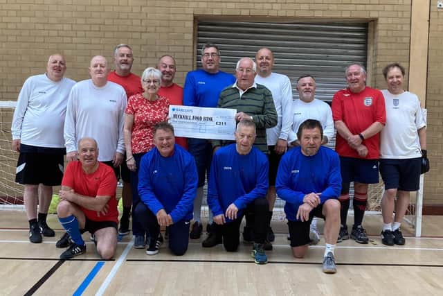 Members of the Geri-Hat-Tricks walking football team present the cheque to Yvonne Campbell of the food bank
