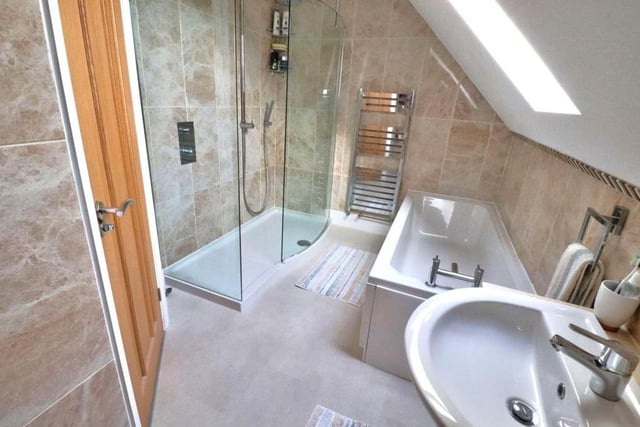 Completing our tour of the interior is this contemporary family bathroom. It features a three-piece white suite with bath, a spacious walk-in shower, a fully tiled floor and walls, and also a heated towel-rail.