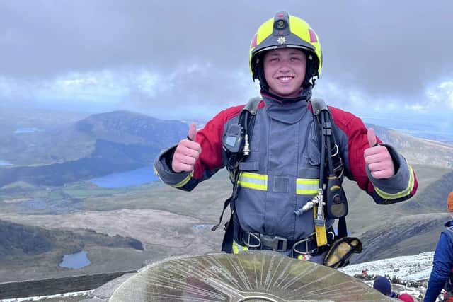 Jude Brough is all smiles at the top of Snowdon after climbing the mountain in full firefighter gear