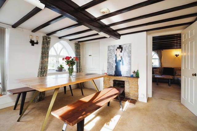 The dining room possesses similar characteristics to the living room, with another feature fireplace and more ceiling beams. An arched window adds to its charm, while the room also includes some handy storage cupboards, as well as stairs leading to the first floor.