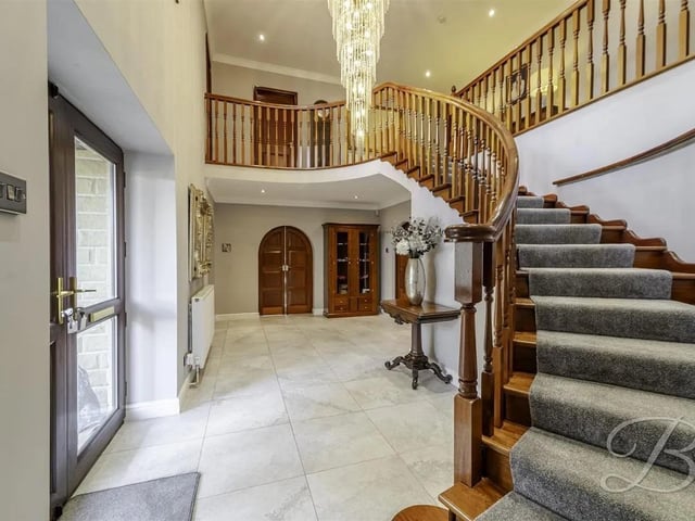 You are welcomed by a grand entrance hallway featuring a sweeping open staircase