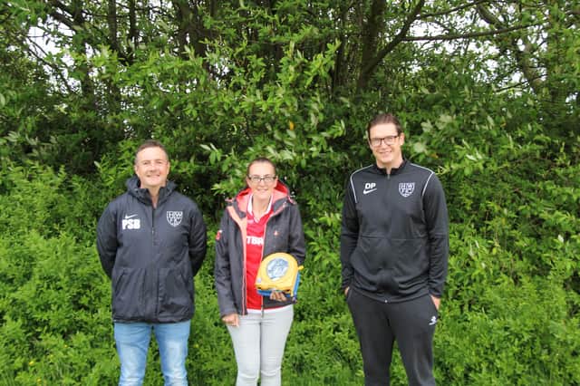 Warriors chairman Paul Burley (left) and Under-7s manager Dan Pheasant receive the mobile defib from Amanda Vennell, founder of Defibs for Grassroots Football