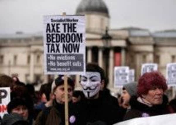 LONDON, ENGLAND - MARCH 30:  Protestors hold signs and wear masks as they demonstrate against the proposed "bedroom tax" gather in Trafalgar Square before marching to Downing Street on March 30, 2013 in London, England. Welfare groups are protesting the government's plans to cut benefits where families have surpassed the number of rooms they require. (Photo by Matthew Lloyd/Getty Images)