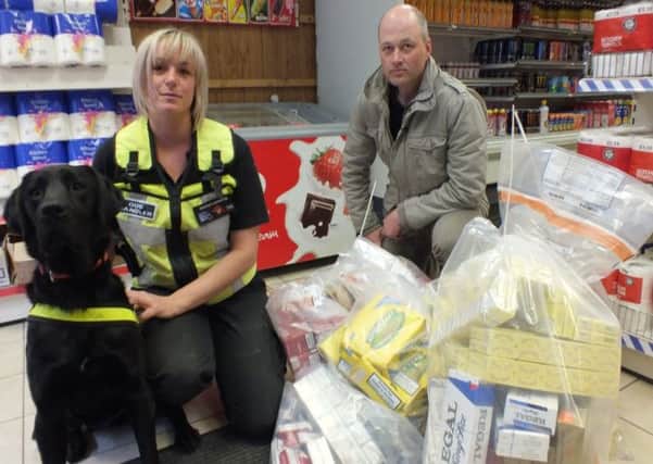 Louise Wilson from Wagtail International Specialist Dog Services, a sniffer dog and Matt Rawson from Nottinghamshire County Councils Trading Standards with the seizure of illicit tobacco products inside Andrews News and Booze on Lower Road in Sutton