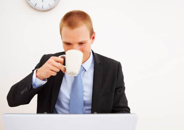 Portrait of a young business executive drinking coffee while looking at the computer
