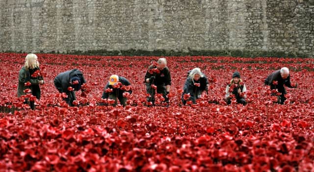 Volunteers remove poppies from the moat of the Tower of London, as work begins dismantling the 'Blood Swept Lands and Seas of Red' installation, which captured the imagination of Britain as it commemorated the centenary of the First World War. PRESS ASSOCIATION Photo. Picture date: Wednesday November 12, 2014. More than five million people have travelled to the Tower of London to see the work since the first ceramic flower was placed in the moat in July. See PA story MEMORIAL Remembrance. Photo credit should read: John Stillwell/PA Wire