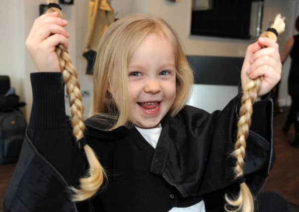 Frankie Walters holds up her plaits which she will donate to the Little Princess Trust.