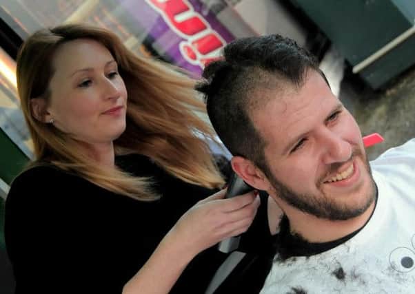 Emma Shucksmith of 'Classic hair & Beauty' Mansfield cuts off half the hair and beard belonging to Theo Keliris of  Mansfield's Black Pearl fish and chip shop