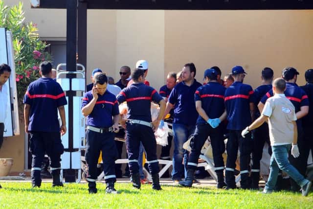 Injured people are treated near the area where an attack took place in Sousse, Tunisia. A young man unfurled an umbrella and pulled out a Kalashnikov, opening fire on European sunbathers in an attack that killed at least 28 people at a Tunisian beach resort. (AP Photo/Hassene Dridi)