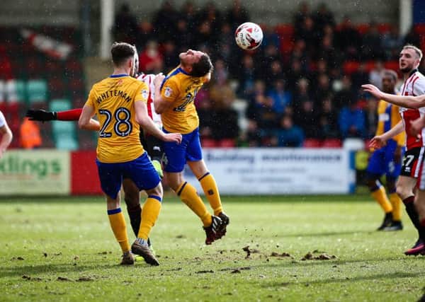 Mansfield Town's Jamie McGuire heads the ball on - Photo by Chris Holloway